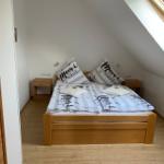 Doppelbett mit Bettwäsche, zwei Nachttische und Dachschräge mit Fenster.
