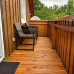 Holzterrasse mit Sitzgelegenheit und Blick auf Bäume.