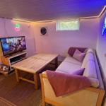 Wohnzimmer mit Sofa, Tisch, Fernseher und Neonbeleuchtung an den Wänden.