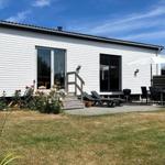Wohnhaus mit Terrasse, Liegen und Grill. Garten mit Rosen und Gras.