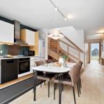 Küche mit Esstisch, Stufen zur oberen Etage und Holzwand.