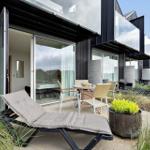 Terrasse mit Liegestuhl und Tisch. Im Hintergrund moderne Containerhäuser.