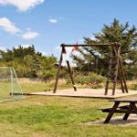 Hinterhof mit Sandkasten, Schaukel und Fußballtor auf Grünfläche.