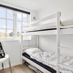 Zimmer mit Doppelstockbett, Fenster und Stuhl mit Sitzhöhenverstellung.