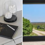 Wohnzimmer mit schwarzen Ledermöbeln, großer Glasfront und Holzboden.