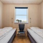 Zimmer mit zwei Betten, Holzwand und Fenster. Schwarze Stuhl und Wandbild.