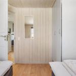 Zimmer mit zwei Betten, Fenster und Kleiderschrank. Holzwände und Holzboden.