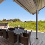 Terrasse mit Esstisch und Stühlen, Blick auf grüne Vegetation und Häuser