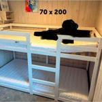 Doppelstockbett mit Matratzen und Kissen. Wand mit Holzverkleidung und Gemälde.