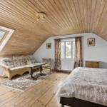 Schlafzimmer mit Holzdecke, Dachfenster und weißem Schrank.