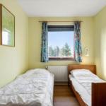 Ein Schlafzimmer mit einem Bett, einem Stuhl und einem Fenster mit Blick auf Bäume.
