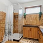Badezimmer mit Toilette, Waschbecken und Spiegel an orangefarbenen Fliesen.