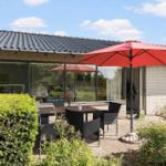 Ein modernes Haus mit Blumenbeet und Terrasse unter blauem Himmel.