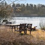 Außenbereich mit Feuerkorb und Holztisch mit Stühlen am See