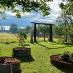 Haus mit rotem Dach, Garten und Blick auf Wasser und Felder.