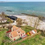 Haus mit rotem Dach und Garten neben Strand und Meer.