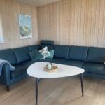 Wohnzimmer mit Sofa, Fernseher und Fenstern zum Blick nach draußen.