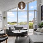 Wohnzimmer mit grauem Sofa, TV und großem Fenster zur Aussicht.