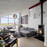 Wohnzimmer mit Kamin, Sofa, Sessel und großem Fenster. Treppenhaus rechts.