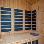 Sauna mit Holzwand und blauen Sitzbänken, ein Handtuch liegt auf der Bank.