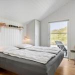 Schlafzimmer mit Bett, Schrank und Fenster zum Balkon mit Sicht auf Gras.