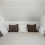 Ein Bett mit Kissen und Decke in einem Raum mit weißen Wänden und Decken.