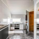 Badezimmer mit Dusche, Toilette und Sauna. Weiße Wände und dunkle Fliesen.