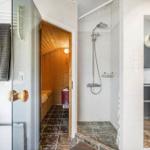 Dusche, Sauna und Küche in einem Raum mit weißen Wänden und dunklem Boden.