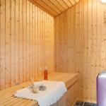 Sauna mit Holzwand, Sitzbank, Flasche, Glas und Handtuch.