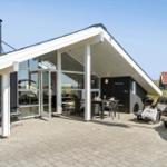 Terrasse mit Grill, Liegestühlen und Blick ins Haus. Glasfront und schwarz-weiße Fassade.