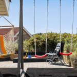 Terrasse mit Hängemattenschaukel und rotem Schaukelstuhl, Spielzeug und Sitzgelegenheiten.