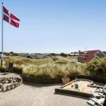 Terrasse mit Sandkasten, Flagge und Gartenmöbeln. Hintergrund: Dänenflagge und Ferienhäuser.