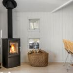 Kaminofen mit Holzstapel, Essbereich und Fenster im Wohnraum.