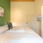 Schlafzimmer mit Bett, grüner Wand und Wandbild