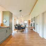 Küche mit Essbereich und Wohnzimmer im offenen Grundriss mit Holzboden und hohem Dach.