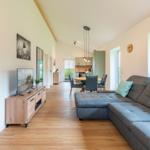 Wohnzimmer mit Sofa, TV und Essbereich im Hintergrund.