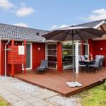 Red vacation home with terrace, umbrella, and garden furniture.