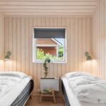 Two beds in a room with wooden walls and a window. A small chair is next to the window.
