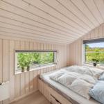 Bedroom with wooden walls, bed, and windows to the garden.