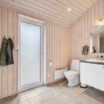 Bathroom with wooden walls, toilet, sink, and shower.