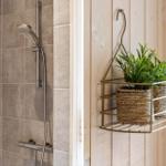 Shower with stainless steel faucet and plants in rack