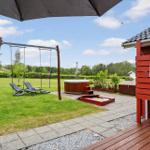 Backyard with hot tub, swing, and terrace. Red wooden structure with shower facility.