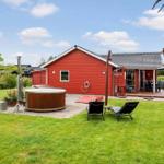 Red holiday home with hot tub, lounge chairs, and terrace in the garden.
