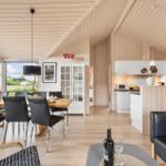 Modern kitchen and dining area with wooden walls and black chairs.