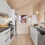Kitchen with white cabinets, dark countertops, and wooden walls.
