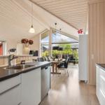 Kitchen with dining area, wooden walls, and large window. White cabinets, black countertop.