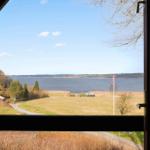 Blick aus dem Fenster auf einen See mit Grünflächen und einigen Häusern im Hintergrund.