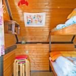 Zimmer mit Holzwand, Doppelstockbett und bunten Stühlen