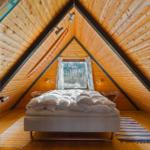 Schlafzimmer mit Holzwand und Dachfenster. Bett mit weißer Bettwäsche.
