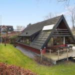 Holzhaus mit Terrasse, Garten und Blick auf Wald. Einrichtung im Inneren sichtbar.